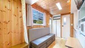 Un interior de madera con un sofá, una ventana y una puerta.