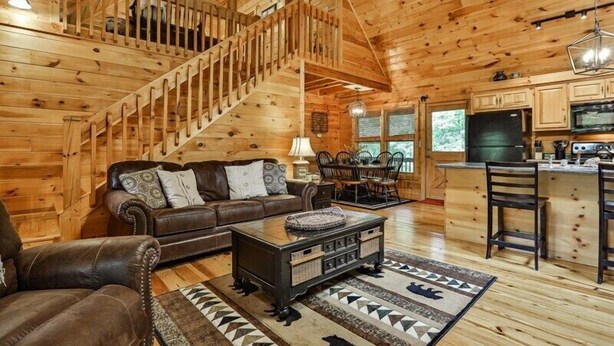 A wooden cabin interior with a staircase, living room, dining area, and kitchen. - The Hideaway at Blue Ridge | Blue Ridge, GA (Mineral Bluff)