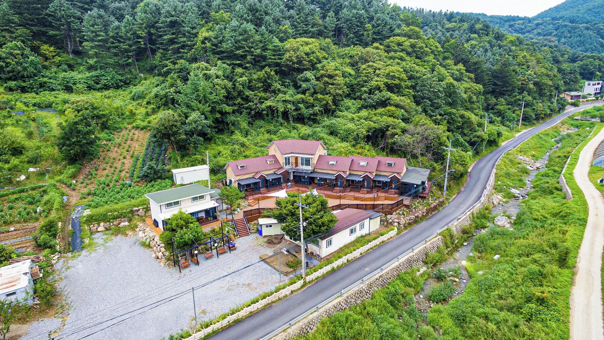 Un edificio grande de varios pisos con un patio central, rodeado de abundante vegetación y un camino sinuoso.