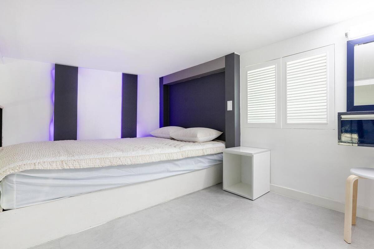 Un dormitorio moderno con cama, mesita de noche y espejo.