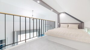 Un dormitorio con una cama grande, una barandilla de cristal y una lámpara moderna.