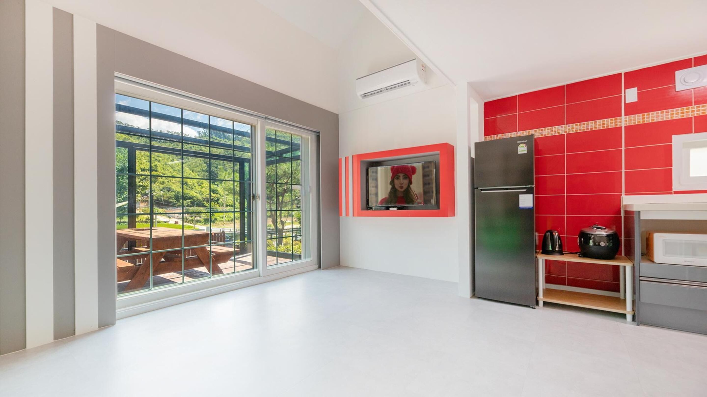 A modern kitchen with a large sliding glass door leading to an outdoor patio, a built-in refrigerator, and a microwave.