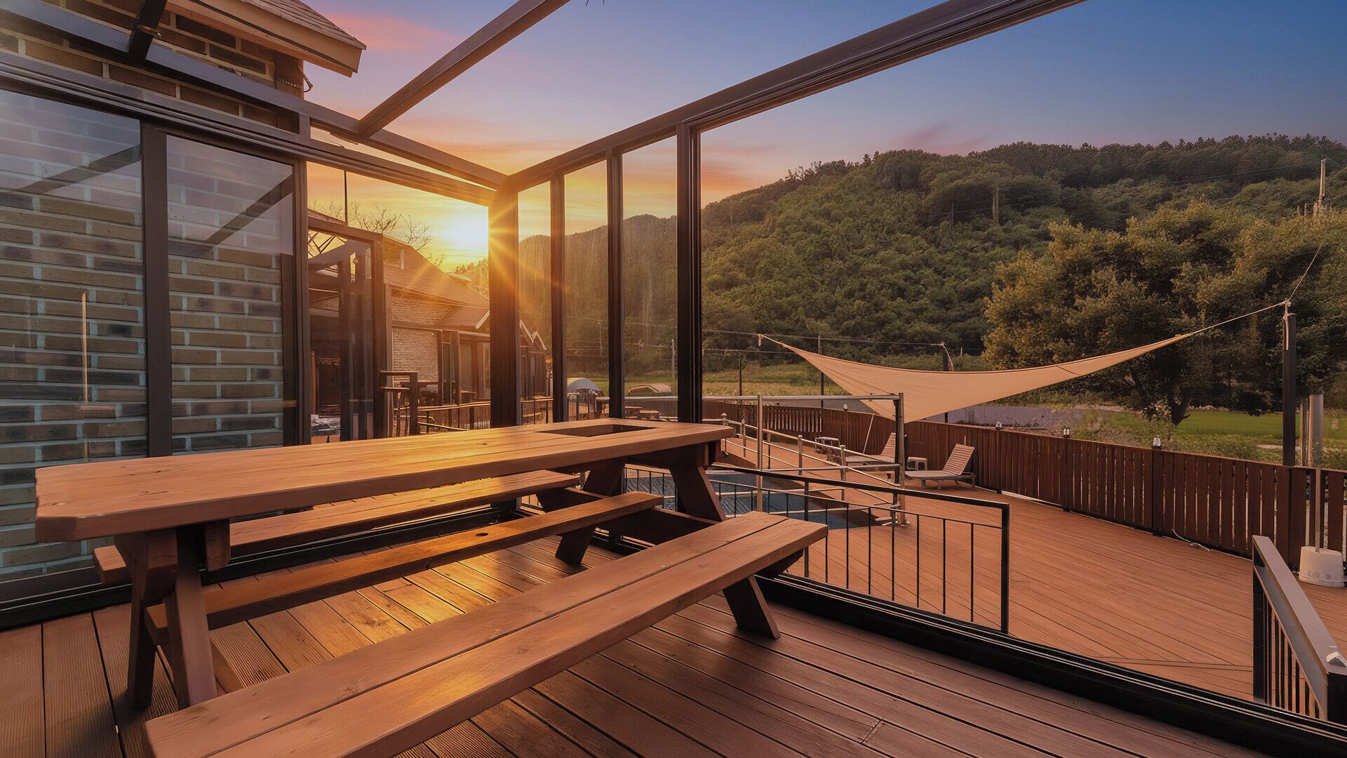 A wooden deck with a table and chairs, overlooking a forested hillside.