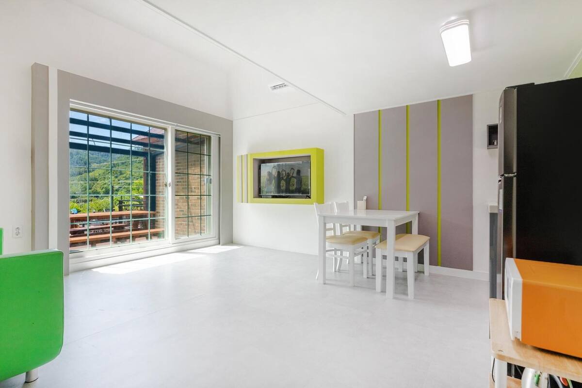 Una habitación moderna con comedor, una silla verde, una mesa y un mueble negro.