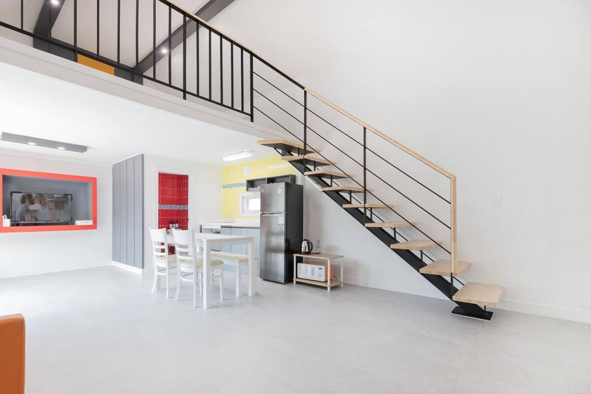 Un interior moderno con una escalera, una zona de cocina y un comedor.