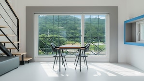 Una habitación moderna con un ventanal grande, una mesa de comedor con sillas, una escalera y una pared azul decorativa.