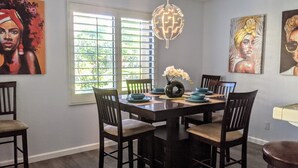 A dining area with a dark wooden table, six chairs, and a vase with white flowers.