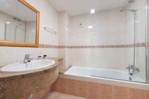 A bathroom with a sink, mirror, and shower area.