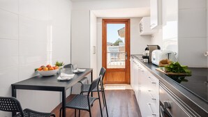 Een moderne keuken met witte kasten, een zwart aanrecht en een houten deur die naar een balkon leidt.