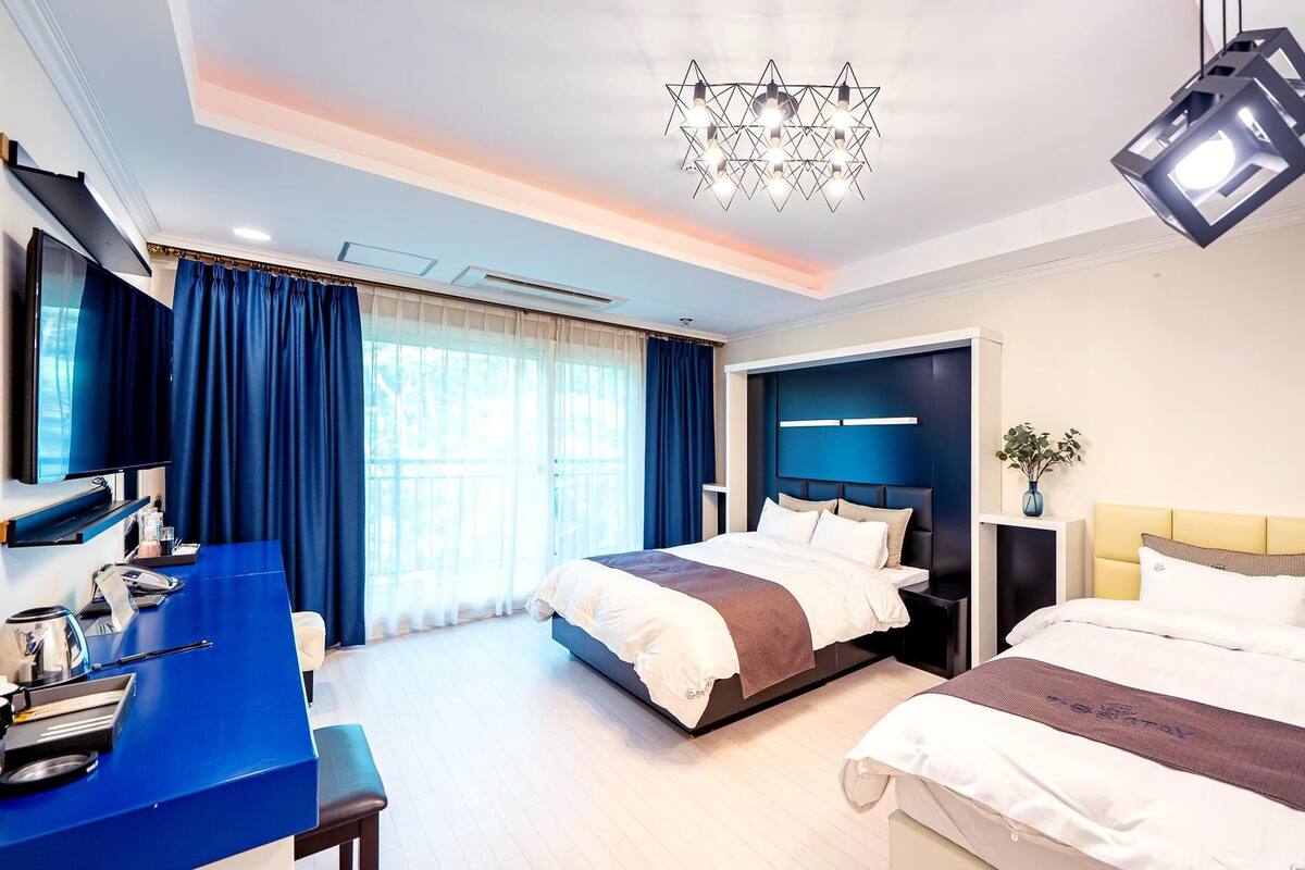 Ein modernes Hotelzimmer mit zwei Betten, einem Schreibtisch, einem Fernseher und einer Kristallleuchtre.