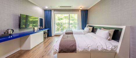 A hotel room with a bed, a desk, a television, and a view of the outdoors.