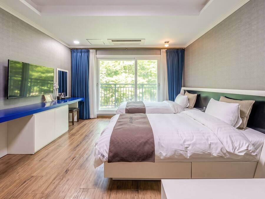 Una habitación de hotel con cama, escritorio, televisor y vistas al exterior.