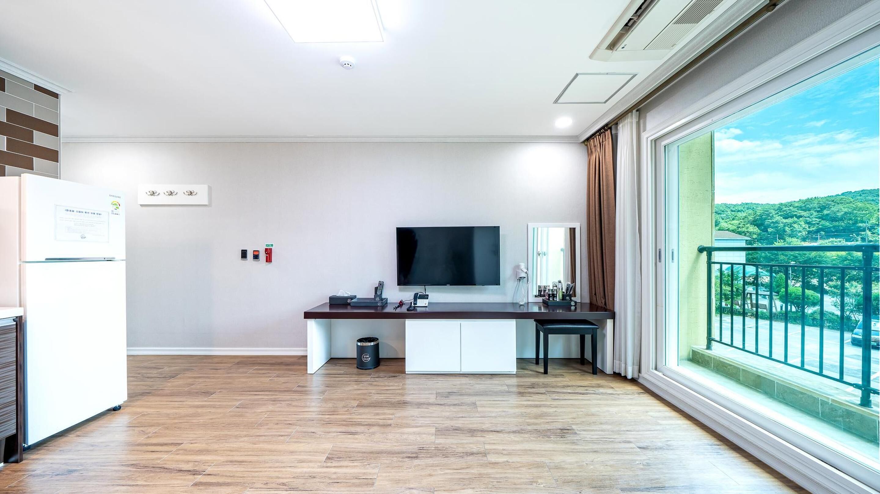 Una cocina moderna con televisión de pantalla plana, una pequeña isla y vistas a un paisaje verde a través de un ventanal amplio.
