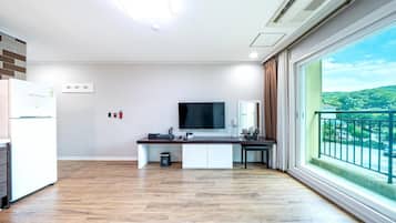 Una cocina moderna con televisión de pantalla plana, una pequeña isla y vistas a un paisaje verde a través de un ventanal amplio.
