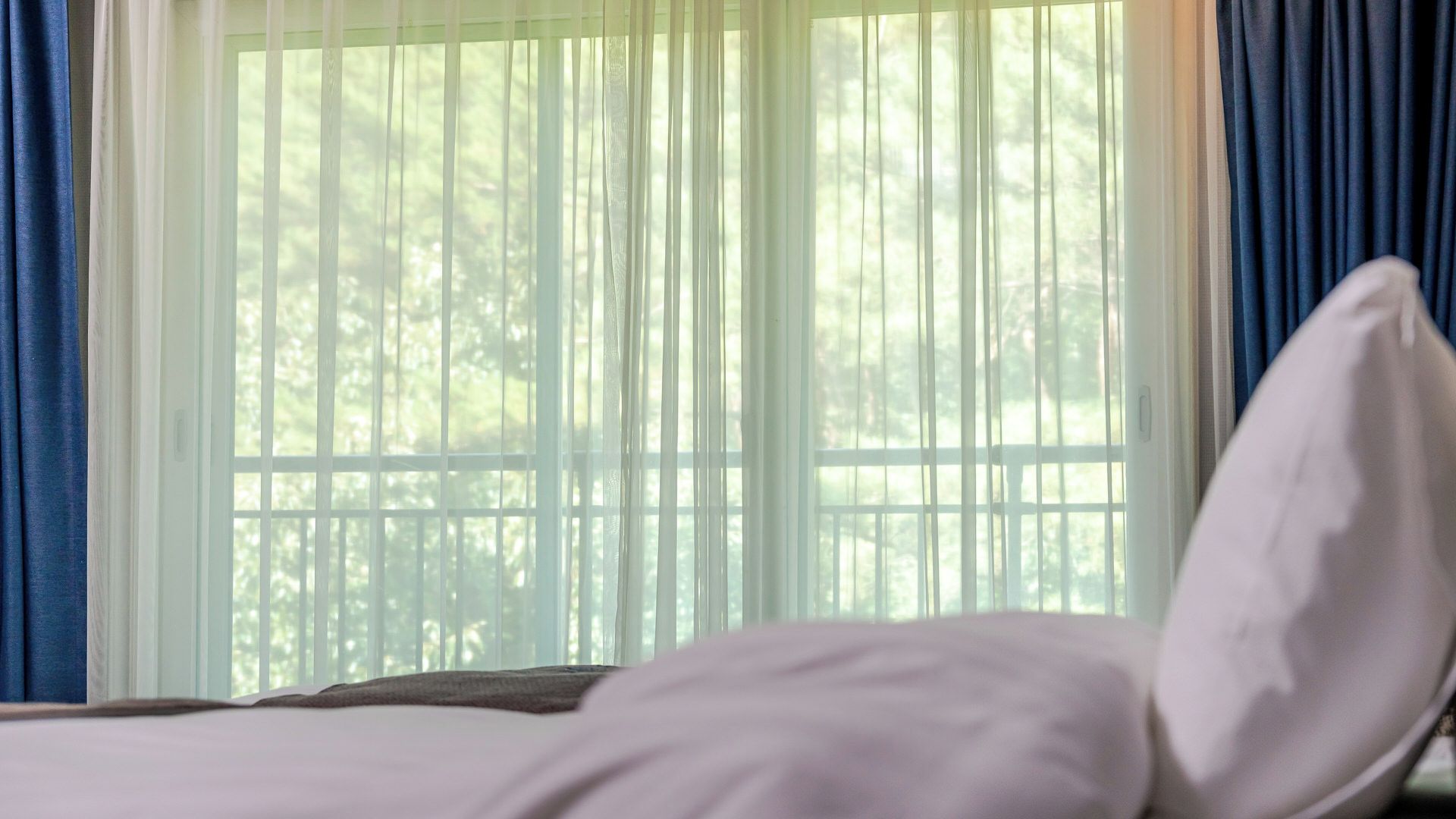 Een bed met wit beddengoed in een kamer met een raam.