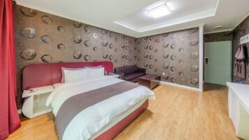 A modern hotel room with a bed, a seating area, and a wardrobe.
