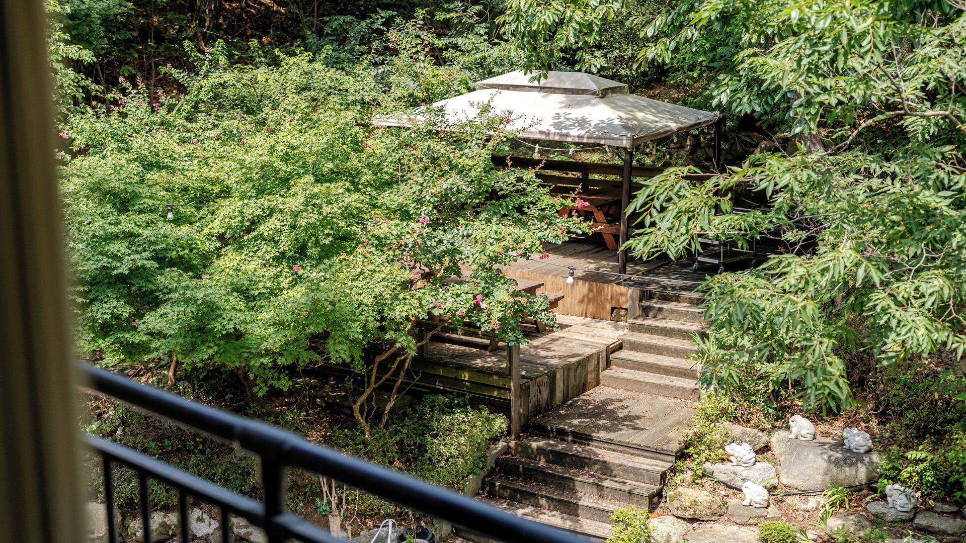 Een tuin met een houten trap naar een prieel.