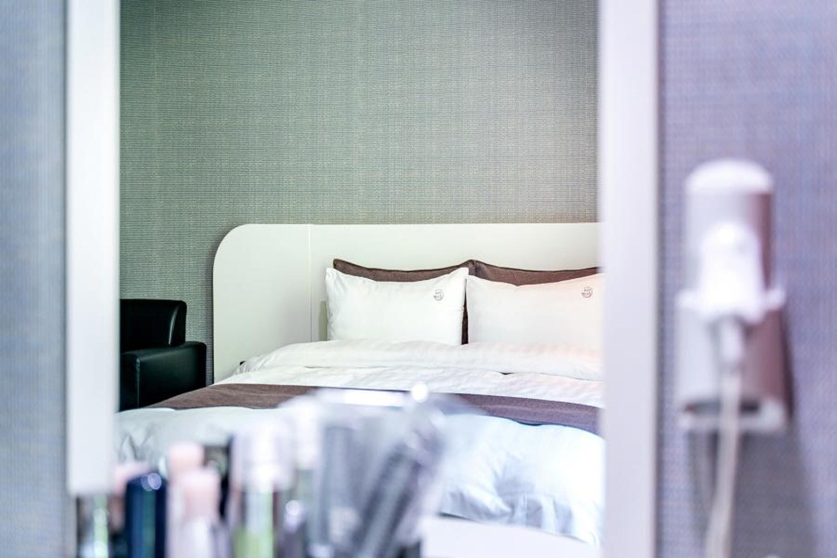 Ein Hotelzimmer mit einem Bett, einem Sessel und einem sichtbaren Badezimmerbereich.