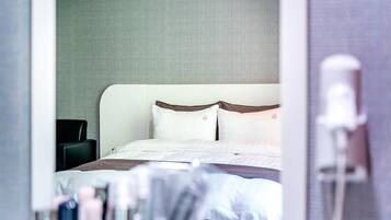 Habitación de hotel con cama, una silla y un baño visible.