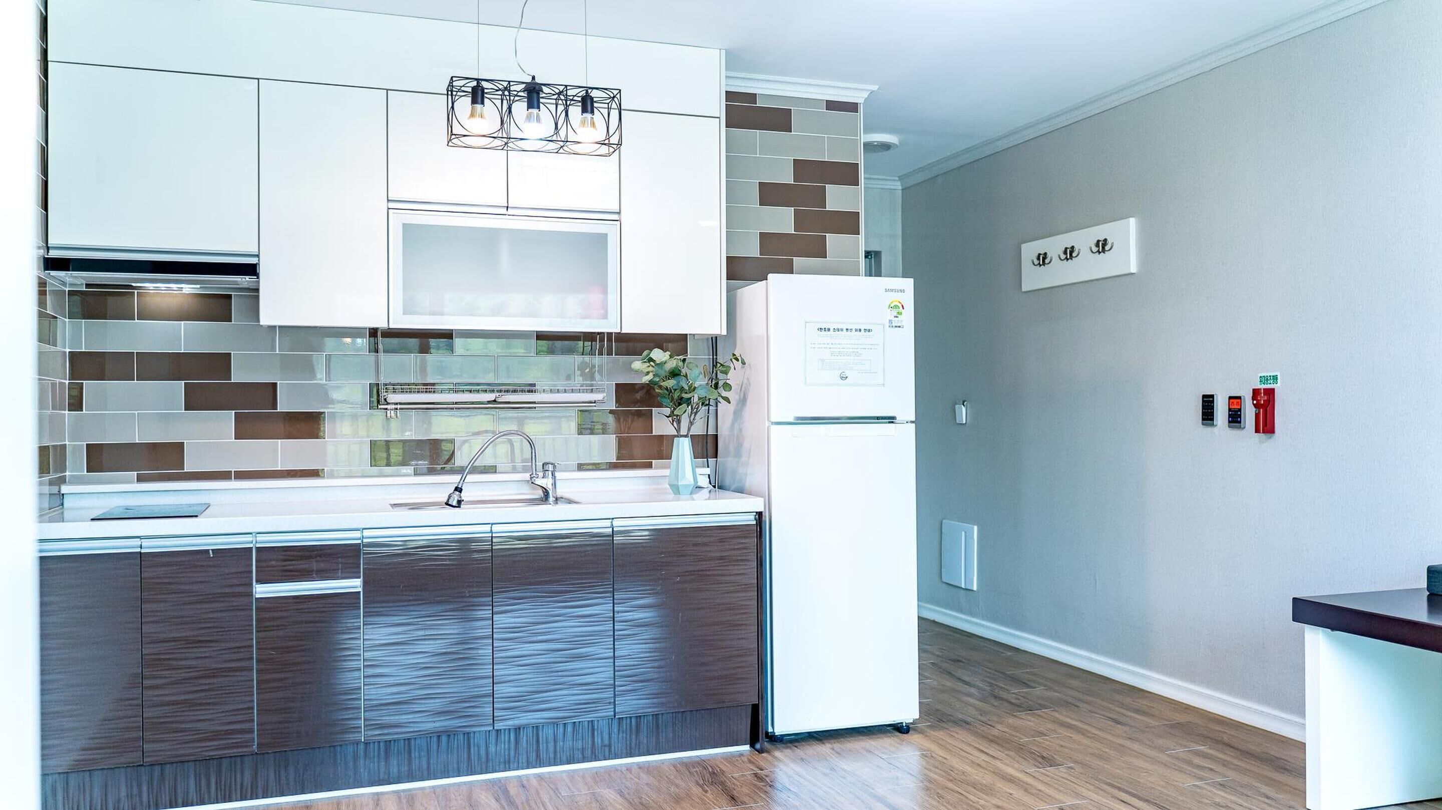 A modern kitchen with a built-in microwave, a stainless steel sink, and a refrigerator.