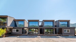 Un immeuble moderne à plusieurs étages, doté de grandes fenêtres et d’une allée gravillonnée.