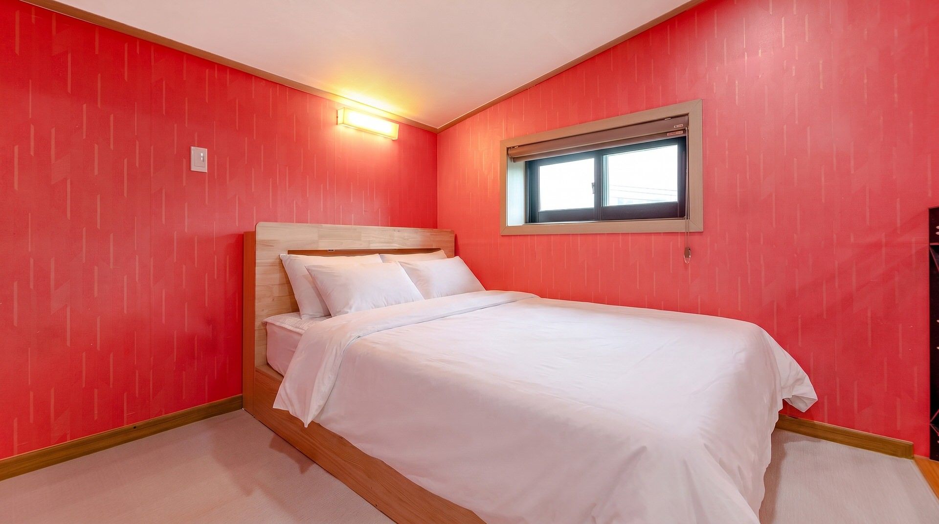 Un dormitorio con una cama individual, paredes rojas y una ventana.