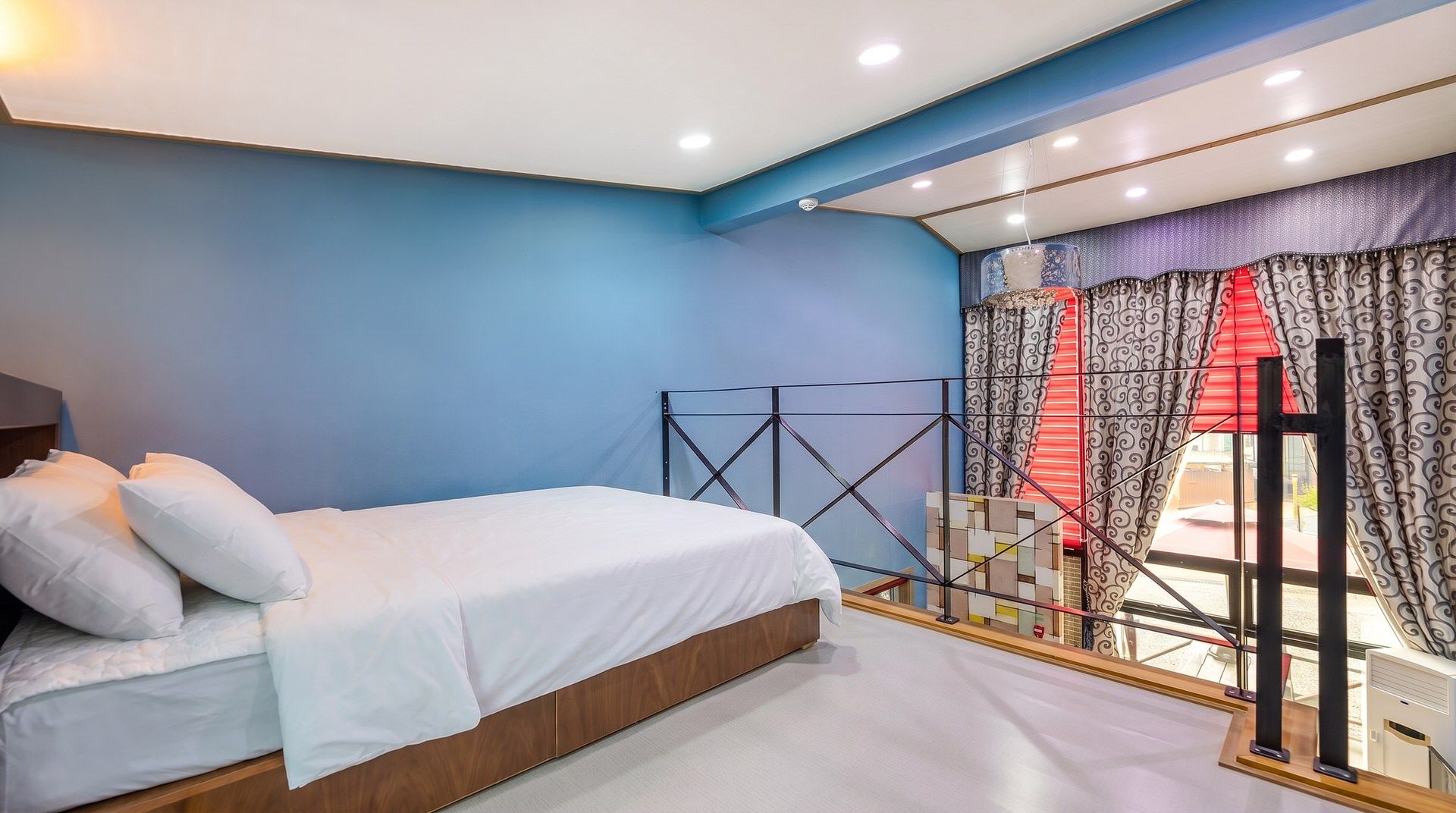 A bedroom with a bed, a window with curtains, and a view of the outside.