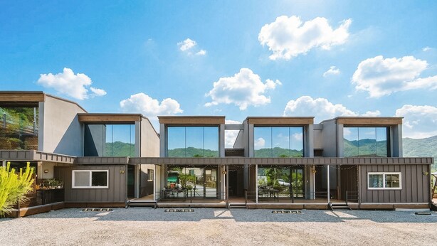 Un bâtiment moderne à plusieurs étages, doté de grandes fenêtres et d’un toit plat, situé dans une région montagneuse.