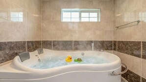Un baño con bañera, ventana y toallero.