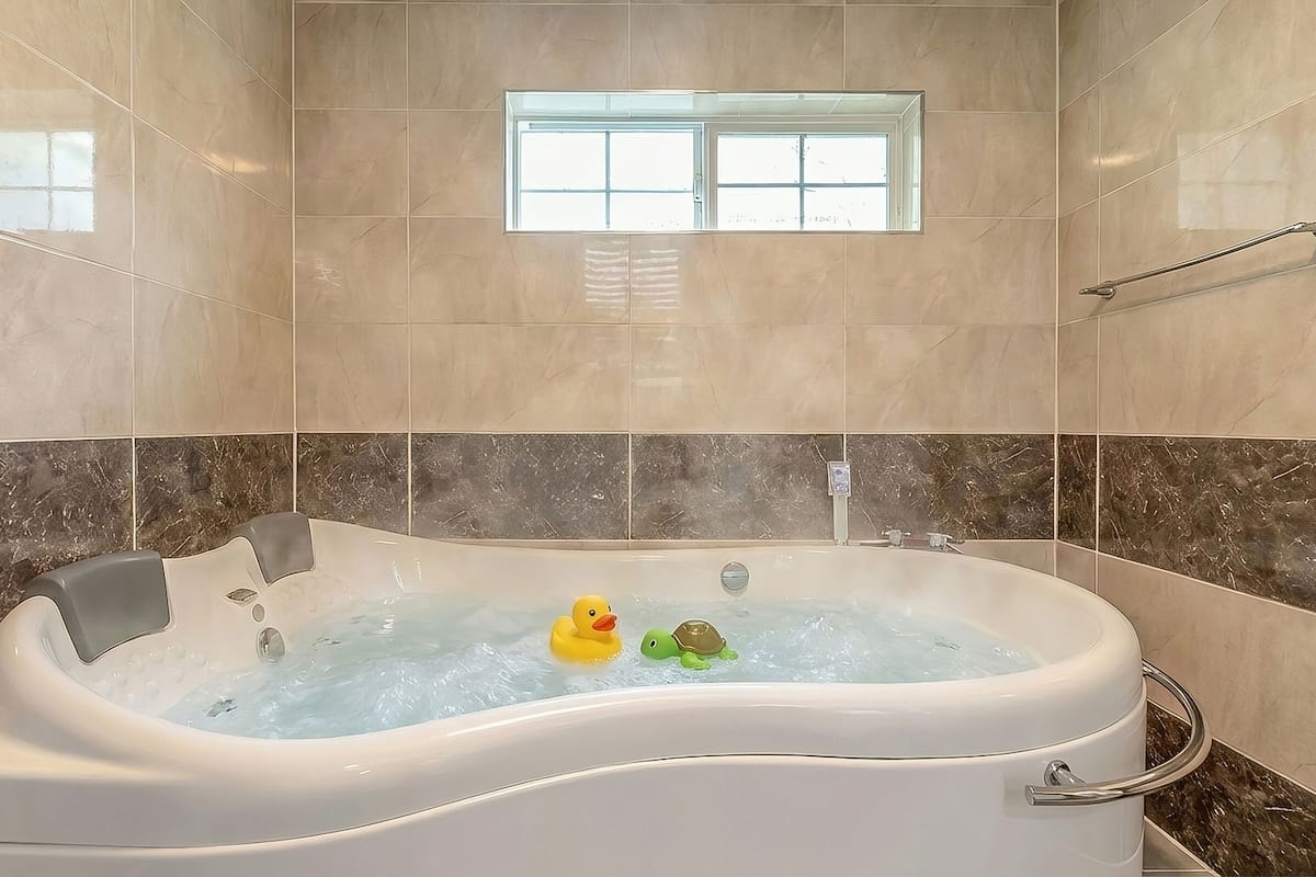A bathroom with a bathtub, a window, and a towel rack.