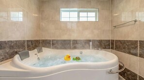 Een badkamer met een bad, een raam en een handdoekhouder.
