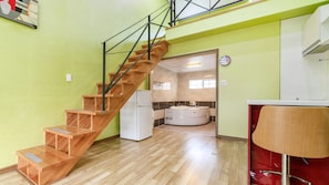 Un intérieur moderne avec un escalier en bois, un coin cuisine et une salle de bain dotée d’une baignoire.