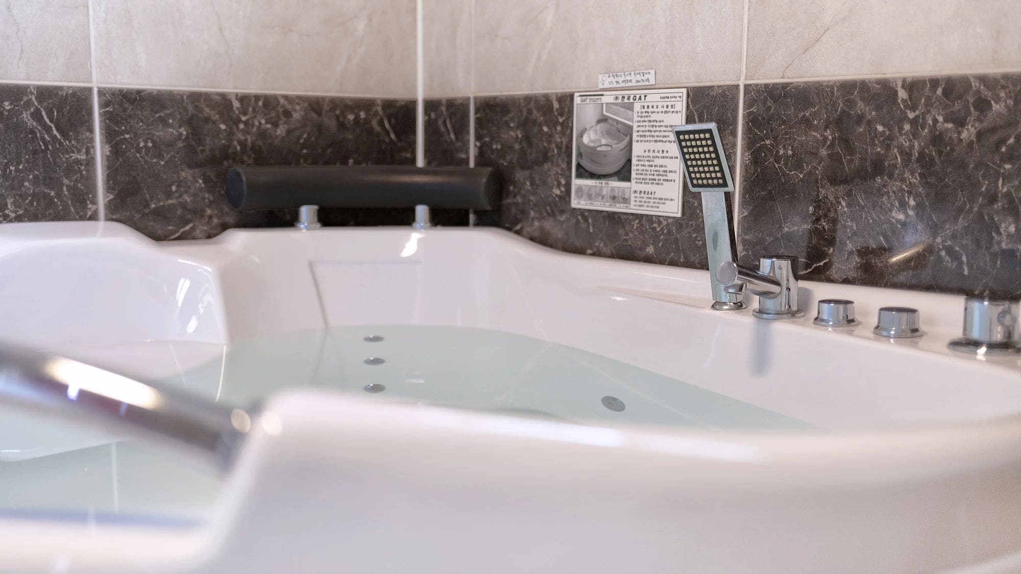 Un baño moderno con una bañera independiente, un cabezal de ducha manual y un panel de control.