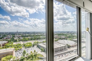 Panoramic city view from a high-rise building, featuring a parking lot, a large building, and a highway.