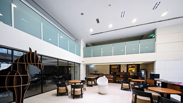 A spacious indoor area with multiple seating arrangements, a large glass wall, and a unique horse sculpture. - CHECK inn Taipei Neihu (Taipei)