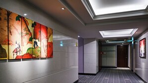 A hallway with patterned flooring, a ceiling light, and a wall with a colorful artwork. - CHECK inn Taipei Neihu (Taipei)