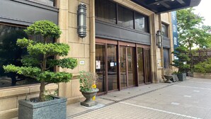 A building with a large entrance, potted plants, and a blue sign. - CHECK inn Taipei Neihu (Taipei)