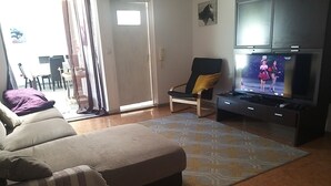 Una sala de estar con un sofá, una televisión, una silla y un tapete estampado.