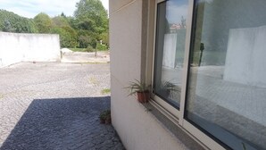 Fachada de un edificio con un patio empedrado, plantas en macetas y un ventanal grande.