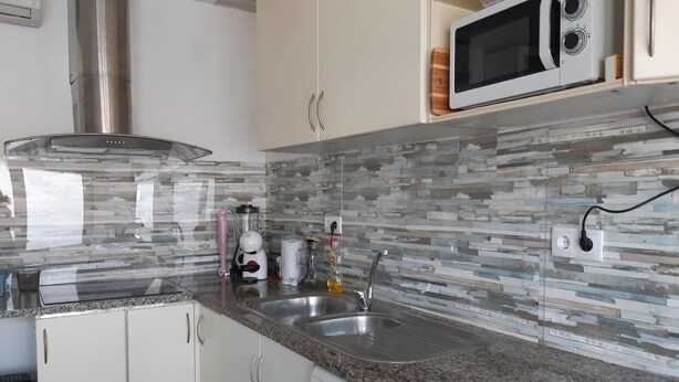 Una cocina moderna con encimeras de granito, electrodomésticos de acero inoxidable y salpicadero de mosaico.