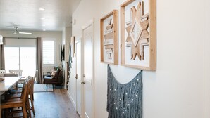 Een hal met houten wanddecoratie, een eethoek met een tafel en stoelen, en een plafondventilator.