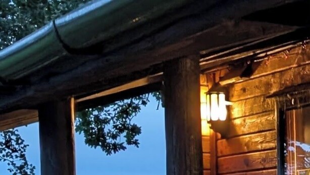 Een houten hut met een veranda, een bank en een bloempot.