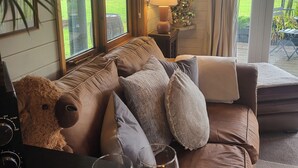 Een gezellige woonkamer met een leren bank, een teddybeer en twee wijnglazen op een dienblad.