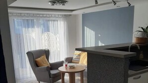 A modern kitchen with a grey countertop, a sink, and a window with sheer curtains. - Lovely 2-Bed Apartment in Coventry (Coventry)