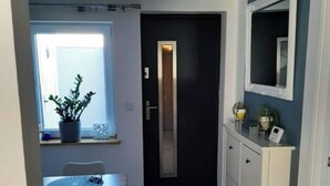 A compact kitchen with a dining area, a dark door, and a white cabinet with a mirror. - Lovely 2-Bed Apartment in Coventry (Coventry)