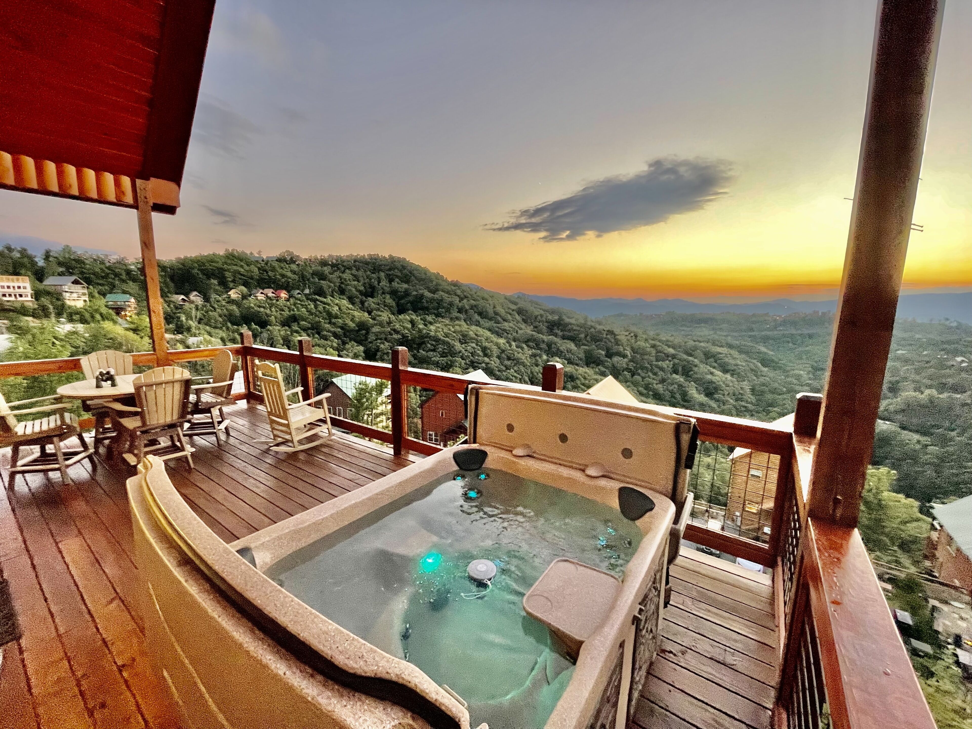 Un jacuzzi en una terraza de madera con vista a un paisaje boscoso.