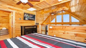 A cozy wooden cabin bedroom with a bed, a fireplace, and a large window. - Cozy 2bedroom cabin near Island / Dollywood at Pigeon Forge  with Panormic Views (Sevierville)