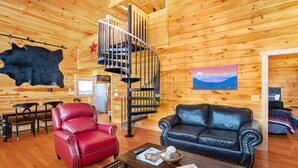 A wooden interior with a spiral staircase, leather furniture, and a painting on the wall. - Cozy 2bedroom cabin near Island / Dollywood at Pigeon Forge  with Panormic Views (Sevierville)