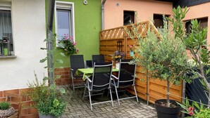 Eine Terrasse mit Tisch und Stühlen, Blumentöpfen und einem Holzzaun.