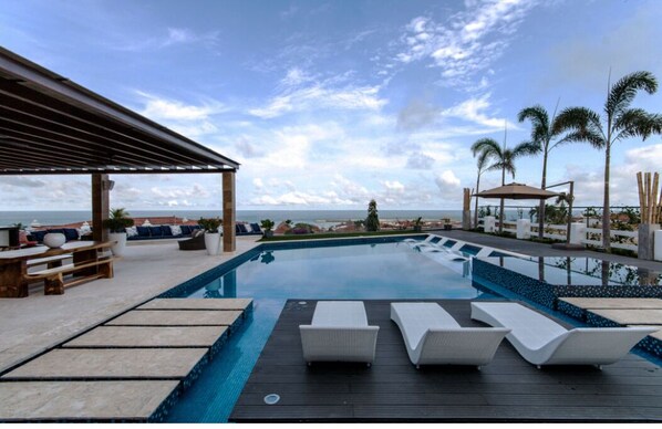 Relax by the ocean with a serene pool surrounded by a deck, lounge chairs, and a shaded seating area.